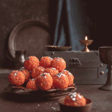 orange motichoor laddoo wedding dessert topped with pistachio and silver