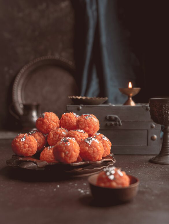 orange motichoor laddoo wedding dessert topped with pistachio and silver