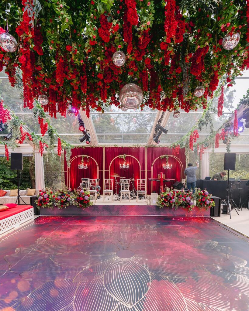 Red roses decor for mehndi event with disco balls and gold chandeliers