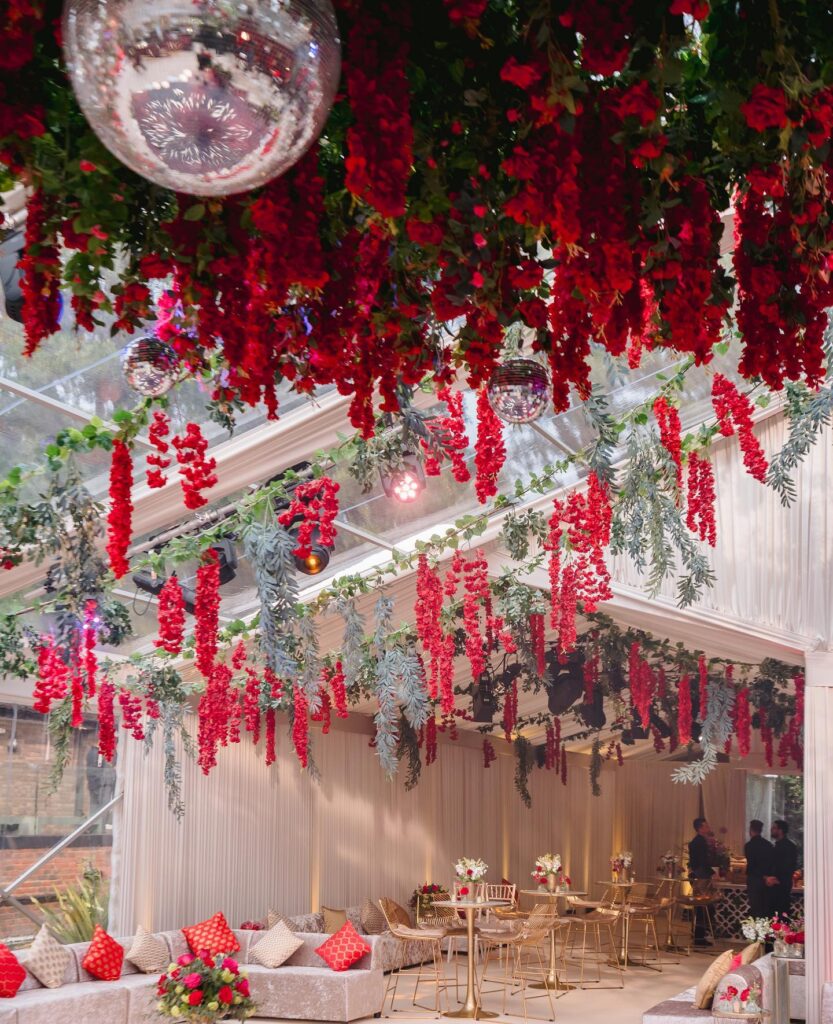 Red roses décor for mehndi event with disco balls and gold chandeliers