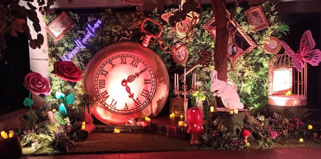 Alice in wonderland party decor with large pocket watch, white bunny and large flowers