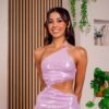 Sarover from Love Is Blind UK season 2, smiling and posing indoors in a sparkling light purple one-shoulder dress with cutout details, surrounded by plants and modern decor.